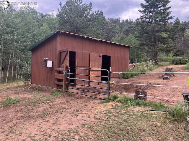 view of outbuilding featuring an outdoor structure, a forest view, and an exterior structure