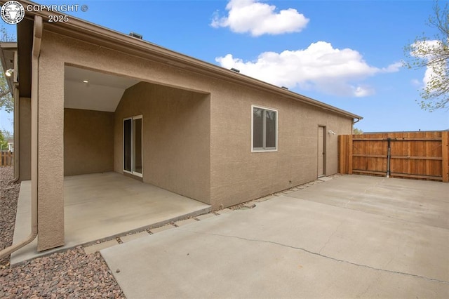 rear view of house with fence, a patio area, and stucco siding