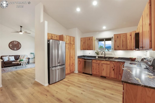kitchen with ceiling fan, appliances with stainless steel finishes, a sink, light wood finished floors, and lofted ceiling