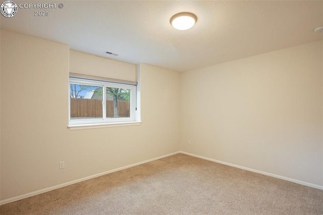 spare room featuring carpet flooring, baseboards, and visible vents