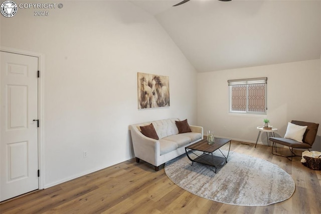 living area featuring baseboards, a ceiling fan, wood finished floors, and high vaulted ceiling