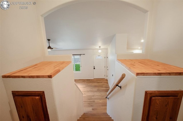 stairs with arched walkways, a ceiling fan, and wood finished floors