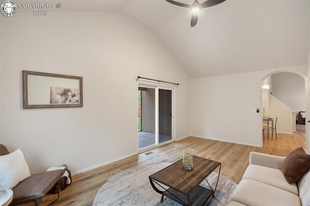 living area with arched walkways, baseboards, a ceiling fan, and wood finished floors