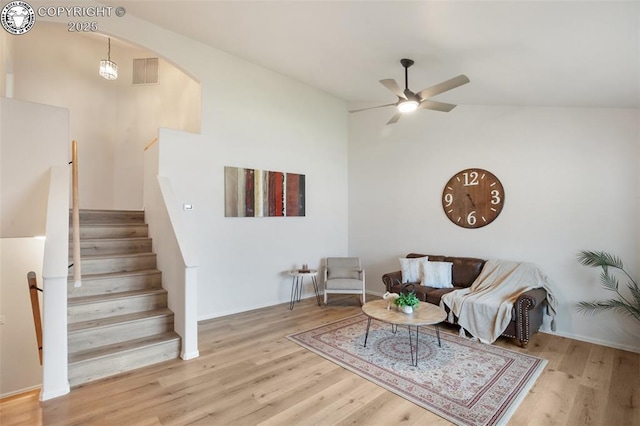 living area with ceiling fan, arched walkways, wood finished floors, lofted ceiling, and visible vents