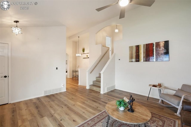 living area with arched walkways, a ceiling fan, visible vents, and wood finished floors