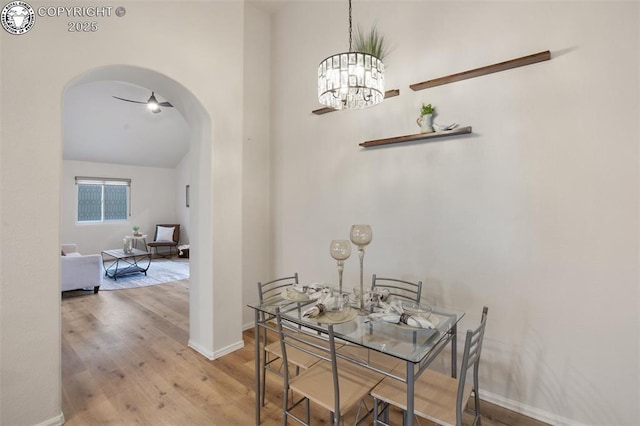 dining space featuring arched walkways, baseboards, wood finished floors, and a chandelier