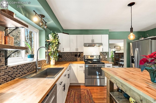 kitchen with wood counters, decorative light fixtures, white cabinetry, and appliances with stainless steel finishes