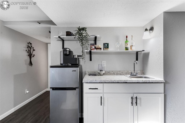 kitchen featuring dark hardwood / wood-style floors, sink, white cabinets, stainless steel fridge, and a textured ceiling