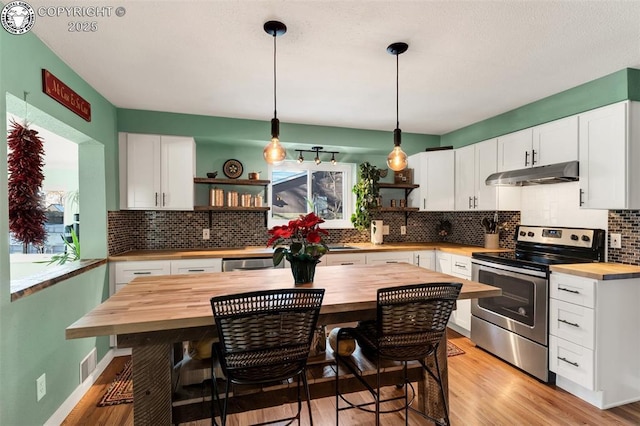 kitchen with a breakfast bar, butcher block countertops, white cabinetry, decorative light fixtures, and stainless steel appliances