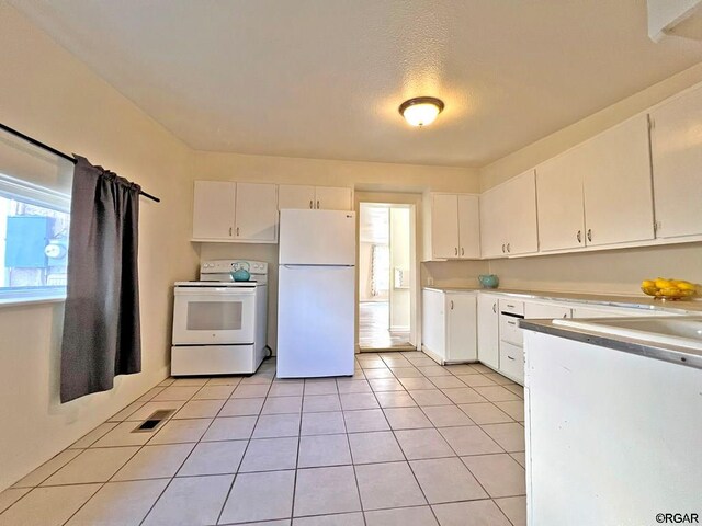 kitchen with white appliances, a textured ceiling, white cabinets, and light tile patterned flooring