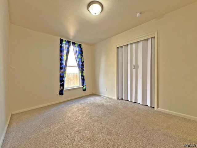 unfurnished bedroom with light colored carpet and a closet