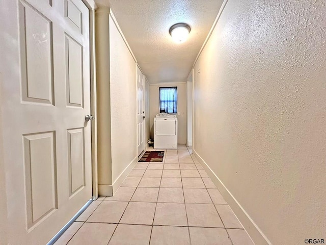 corridor with washer / clothes dryer, a textured ceiling, and light tile patterned flooring