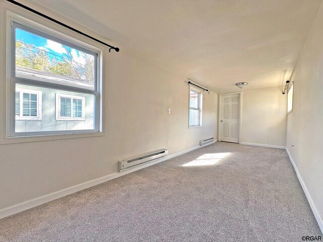 empty room featuring a baseboard radiator, carpet flooring, and a wealth of natural light