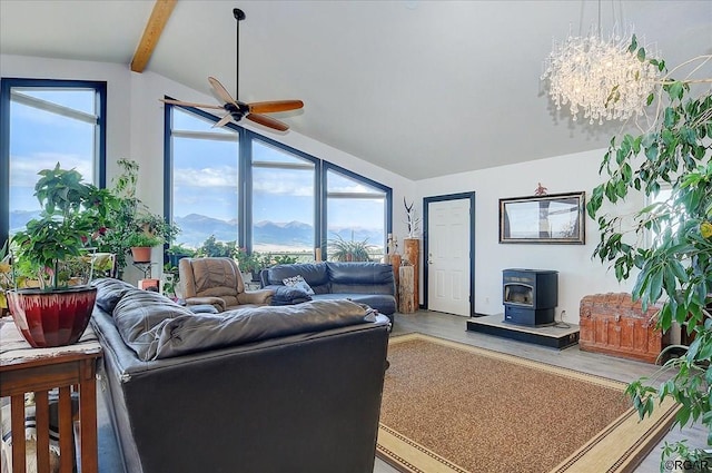 living room with a mountain view, vaulted ceiling with beams, a wood stove, and ceiling fan