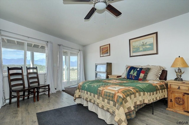 bedroom with ceiling fan, a mountain view, and hardwood / wood-style floors