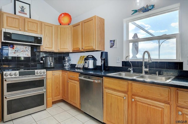 kitchen featuring appliances with stainless steel finishes, tasteful backsplash, lofted ceiling, sink, and light tile patterned floors