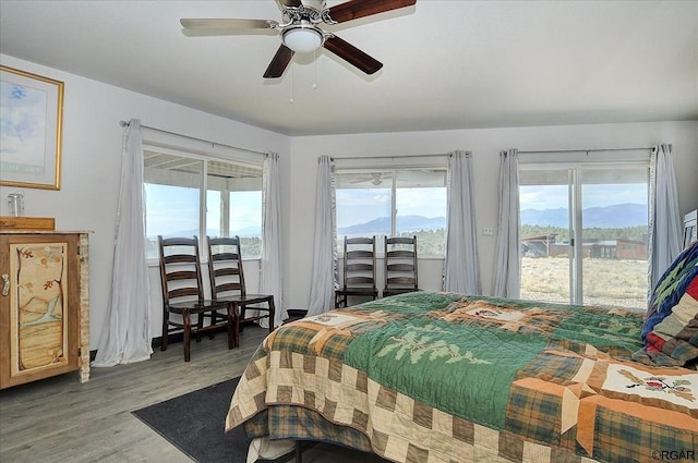 bedroom featuring access to exterior, wood-type flooring, a mountain view, and ceiling fan