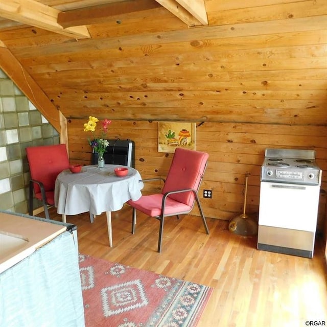 living area featuring beam ceiling, light hardwood / wood-style flooring, and wooden walls