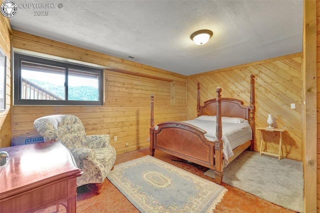 bedroom with visible vents, a textured ceiling, and wood walls