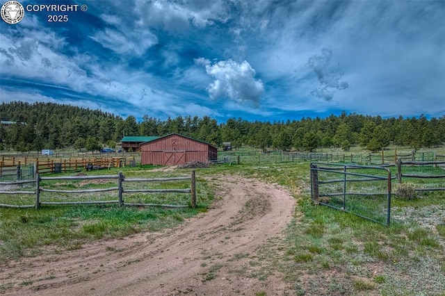 view of gate featuring an outbuilding, a rural view, and fence