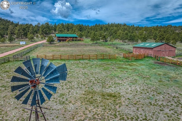 view of yard featuring an outbuilding, a rural view, a wooded view, and fence