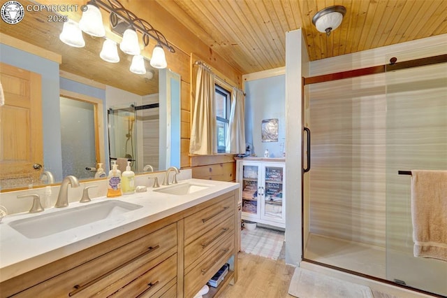 bathroom with double vanity, a shower stall, wood ceiling, and a sink