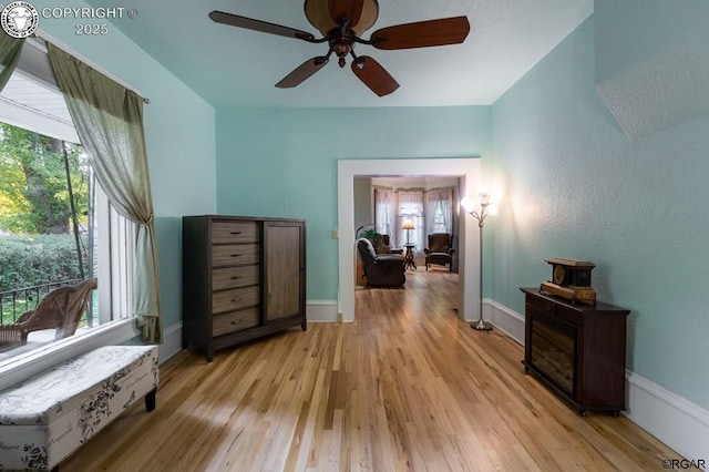 interior space featuring light wood-type flooring, baseboards, and a ceiling fan