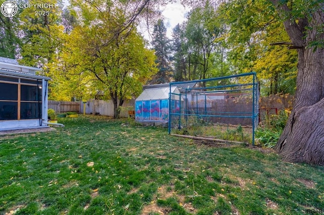 view of yard with a fenced backyard, a greenhouse, and an outbuilding