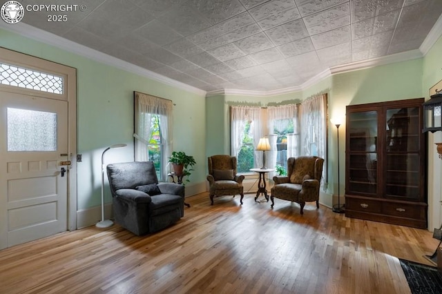 living area with ornamental molding, wood finished floors, and baseboards