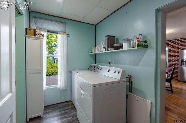 laundry room featuring brick wall, laundry area, washer and clothes dryer, and wood finished floors