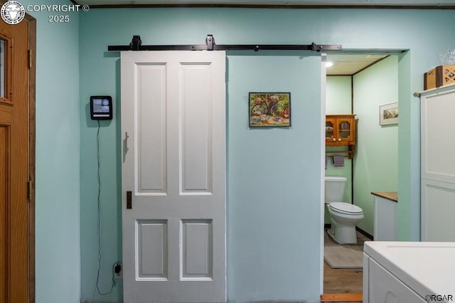 bathroom with washer / clothes dryer, toilet, and wood finished floors