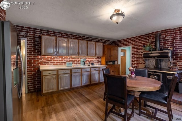 dining space with a textured ceiling, brick wall, wood finished floors, and a wood stove