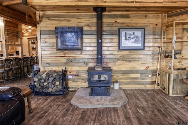 living room with a wood stove, dark hardwood / wood-style floors, and wood walls