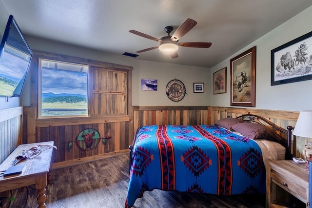 bedroom with hardwood / wood-style flooring, ceiling fan, and wood walls