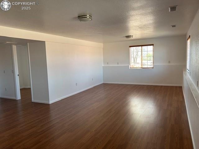600 Pioneer Ln, Florence, CO 81226 - empty room with visible vents, a textured ceiling, baseboards, and dark wood finished floors