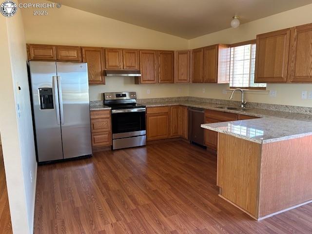 600 Pioneer Ln, Florence, CO 81226 - kitchen with vaulted ceiling, stainless steel appliances, under cabinet range hood, a sink, and brown cabinetry