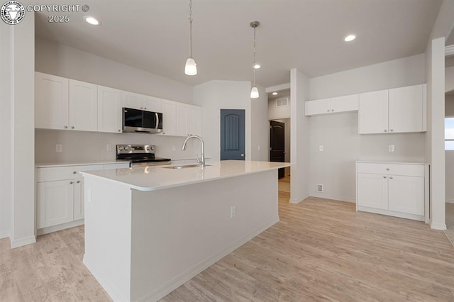 kitchen featuring white cabinetry, stainless steel appliances, sink, and a center island with sink