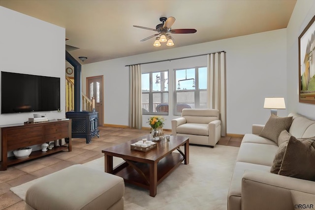 living room featuring a wood stove, light tile patterned floors, and ceiling fan