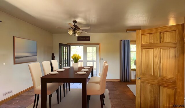 dining space with dark tile patterned floors and ceiling fan