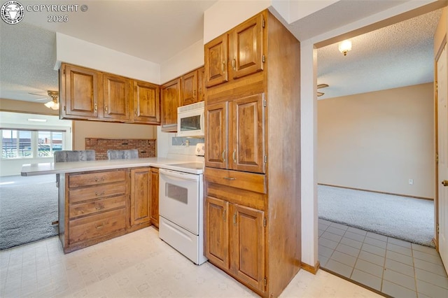 1108 Fairview Ave Unit B, Canon City, CO 81212 - kitchen with white appliances, light colored carpet, ceiling fan, and brown cabinetry