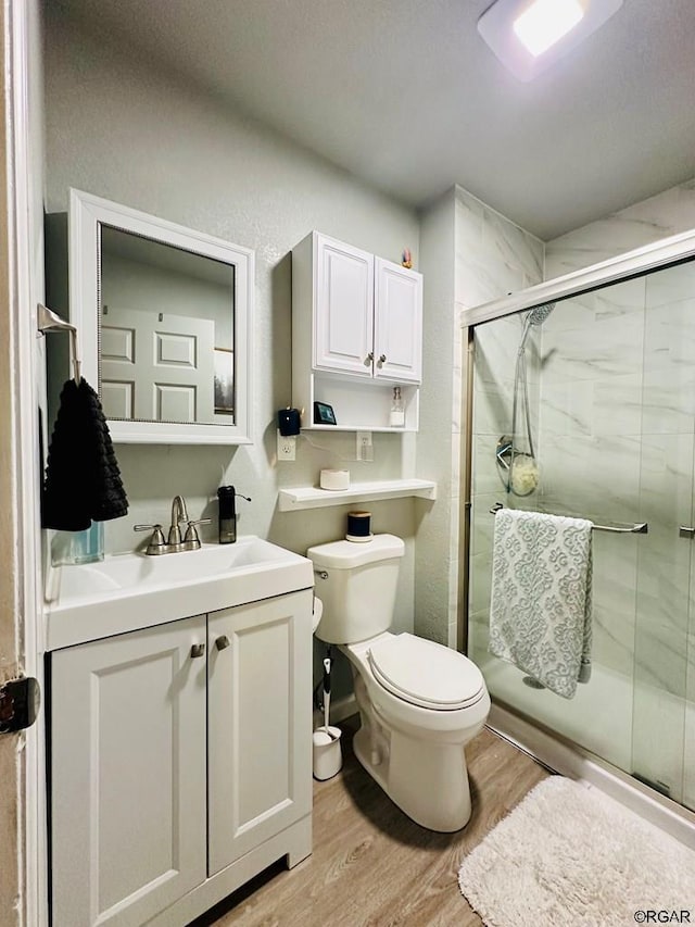 bathroom with wood-type flooring, toilet, vanity, and walk in shower