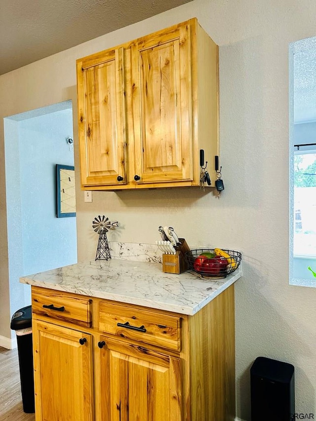 kitchen with light stone countertops, a textured ceiling, and light hardwood / wood-style flooring