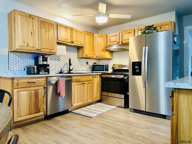 kitchen with sink, light hardwood / wood-style flooring, ceiling fan, stainless steel appliances, and tasteful backsplash