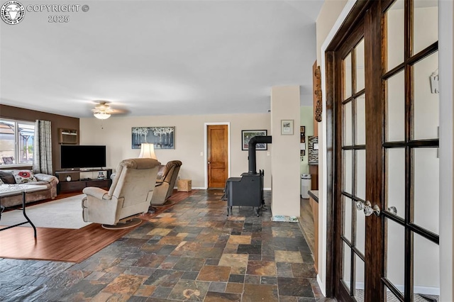 925 2nd St, Penrose, CO 81240 - living area with stone tile floors, a wood stove, and a ceiling fan