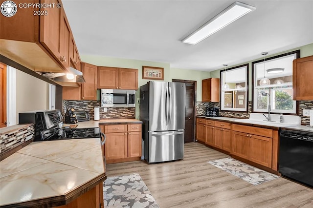 925 2nd St, Penrose, CO 81240 - kitchen featuring stainless steel appliances, decorative backsplash, light wood-type flooring, and brown cabinetry