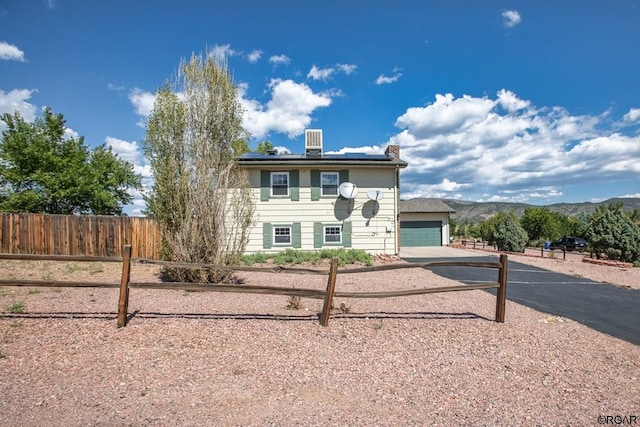 view of front of home with a garage, a mountain view, and solar panels