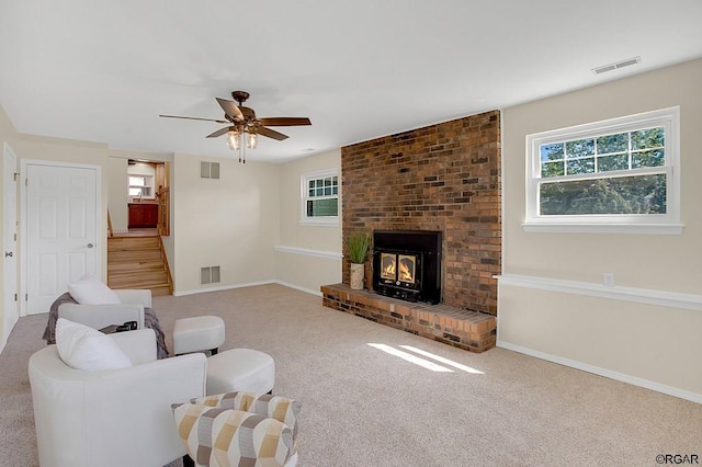 carpeted living room featuring ceiling fan and a fireplace