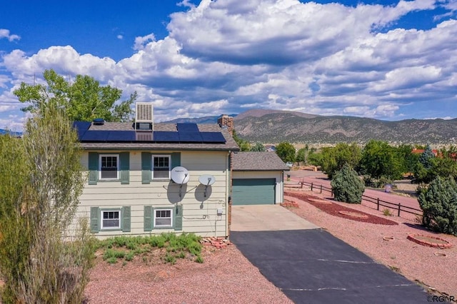 view of front of home with a garage, a mountain view, and solar panels