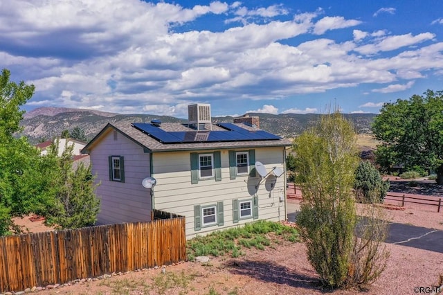 view of front of property featuring a mountain view, central AC unit, and solar panels