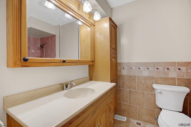 bathroom with vanity, tile walls, tile patterned floors, and toilet